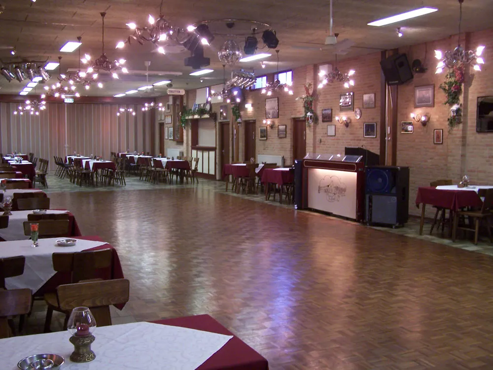 De feestzaal met parketvloer, gedekte tafels en lichtjes aan het plafond